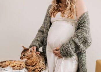 Mujer embarazada acariciando a su gato en casa, convivencia segura y toxoplasmosis en el embarazo